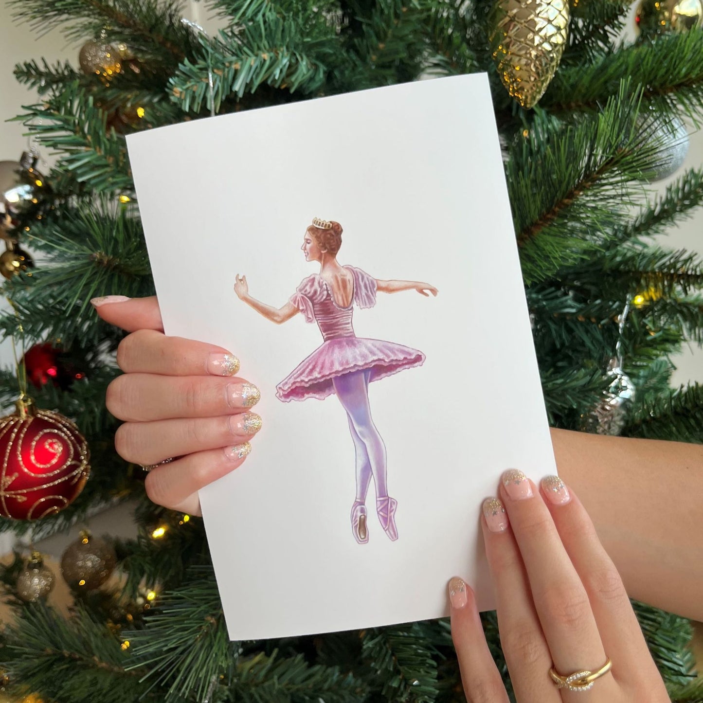 Print of a ballerina wearing a pink costume and golden crown posing gracefully en pointe.